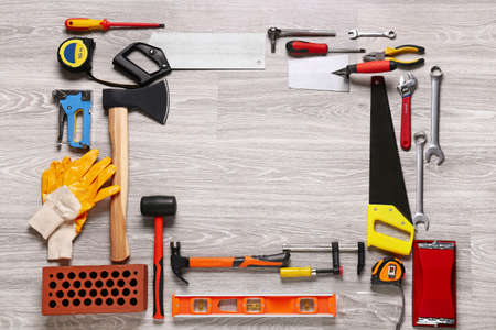 Frame made of construction tools on light wooden background