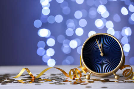 Alarm clock and Christmas decor on table against blurred lights
