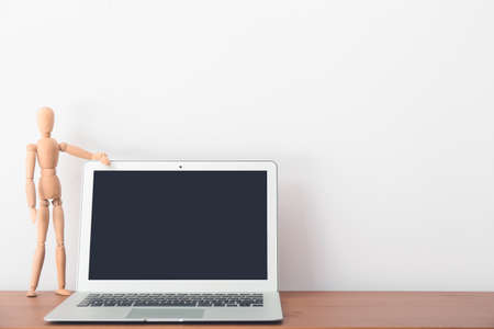 Wooden mannequin with laptop on table in officeの写真素材
