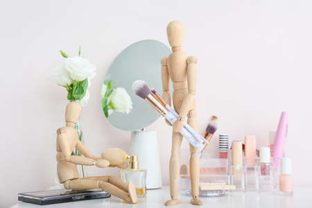 Wooden mannequins with makeup cosmetics and accessories on table in roomの写真素材