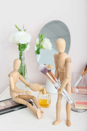 Wooden mannequins with makeup cosmetics and accessories on table in roomの写真素材