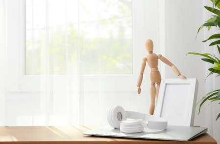 Wooden mannequin with modern devices on table in room