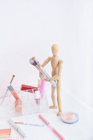 Wooden mannequin with makeup cosmetics and accessories on table in roomの写真素材