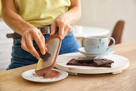 Woman grating chocolate in kitchenの写真素材