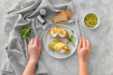Woman eating tasty sandwiches with egg and avocadoの写真素材