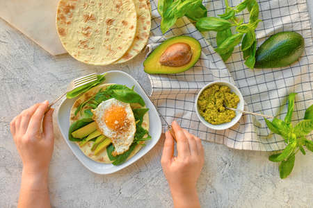 Woman eating tasty fried egg and avocado