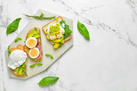 Tasty sandwiches with egg and avocado on white background