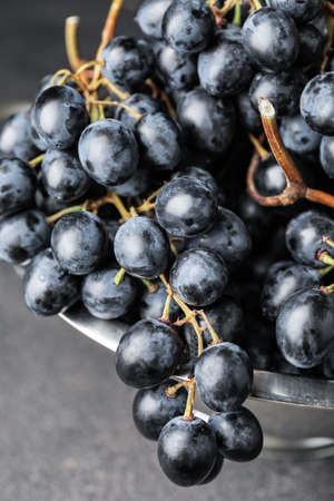 Sweet ripe grapes in colander on table, closeup