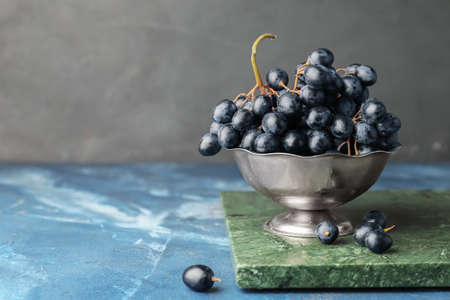 Colander with sweet ripe grapes on table