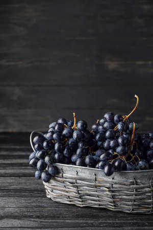 Basket with sweet ripe grapes on table