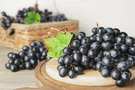 Board with sweet ripe grapes on tableの写真素材