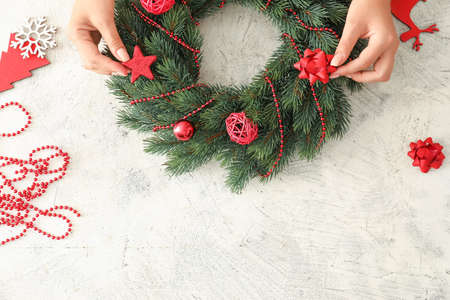 Woman making beautiful Christmas wreath on tableの写真素材
