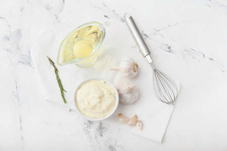 Bowl with garlic sauce and ingredients on white backgroundの写真素材