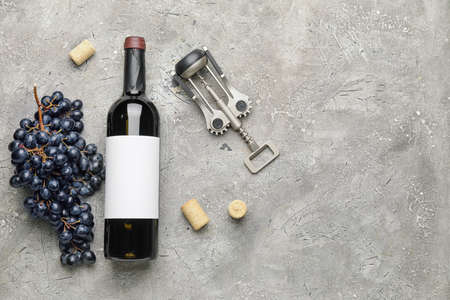 Bottle of red wine with fresh grapes and corkscrew on grunge backgroundの写真素材