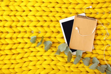 Tablet computer with notebook and earphones on knitted plaidの写真素材