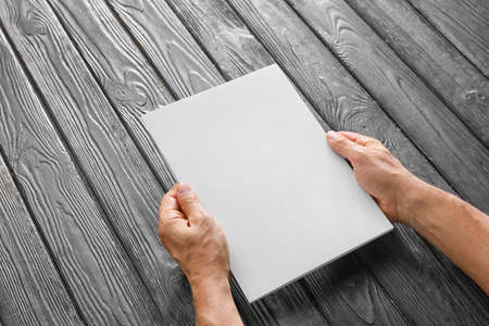 Old man with blank magazine at table