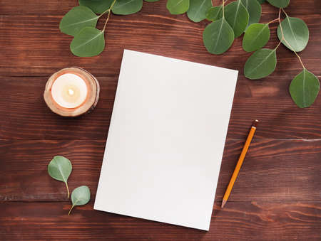 Blank magazine, candle and pencil on wooden background