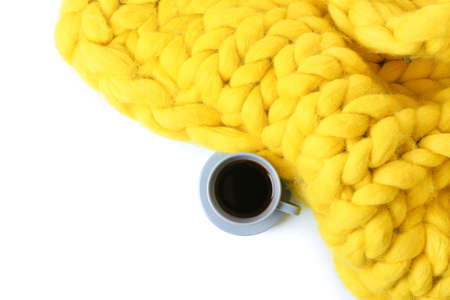 Cup of coffee with knitted plaid on white background
