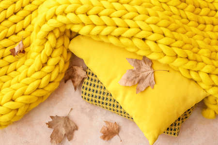 Warm plaids and pillow with autumn leaves on color backgroundの写真素材