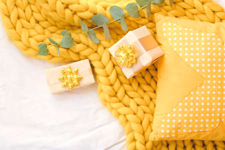 Gifts with pillow and knitted plaid on bedの写真素材