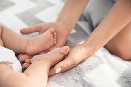 Mother holding feet of her little baby on bedの写真素材