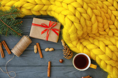 Christmas composition with knitted plaid, cup of tea and gift box on tableの写真素材
