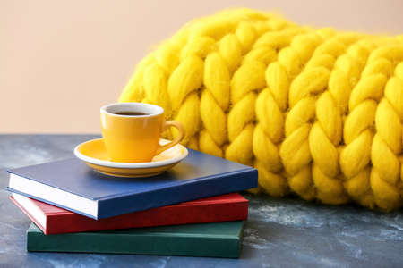 Cup of coffee with books and knitted plaid on tableの写真素材