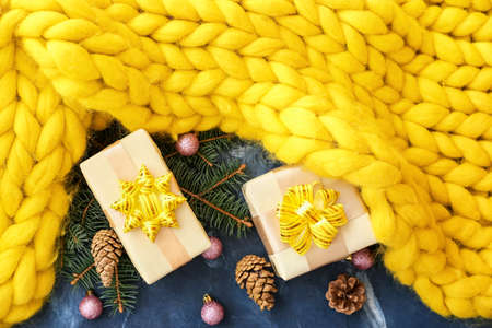 Christmas composition with knitted plaid and gift boxes on color backgroundの写真素材