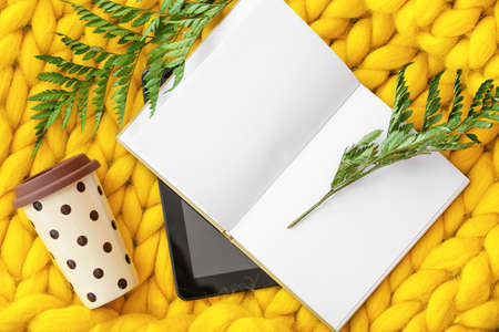 Cup of coffee with book and tablet computer on knitted plaidの写真素材