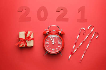 New Year composition with alarm clock and figure 2021 on color background