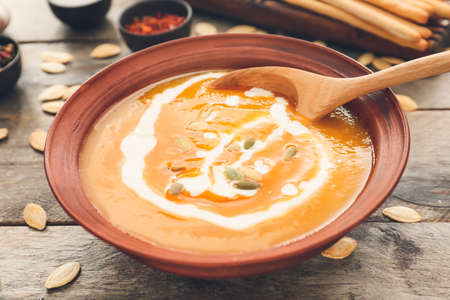 Tasty pumpkin cream soup in bowl on tableの写真素材