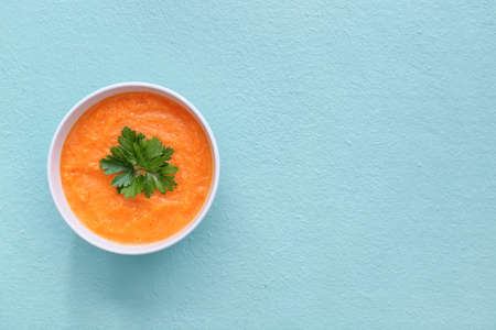 Tasty pumpkin cream soup in bowl on color backgroundの写真素材