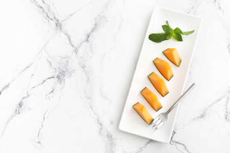 Plate with sweet cut melon on light background