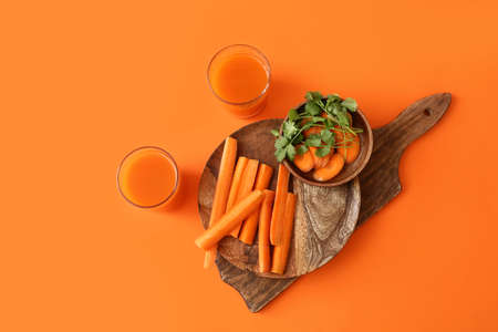Glasses of fresh tasty carrot juice and plate with sliced carrot on color backgroundの写真素材