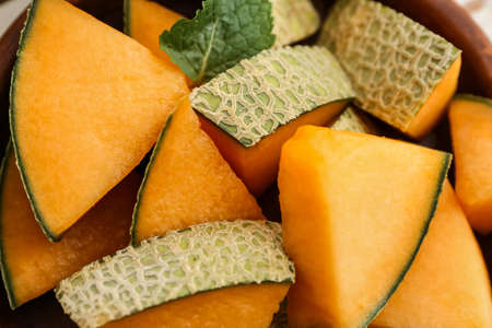 Plate with sweet cut melon on wooden background, closeup