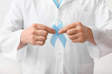 Male doctor with blue ribbon, closeup. Prostate cancer awareness concept