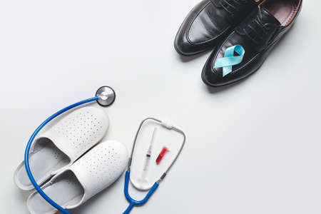 Male shoes with blue ribbon, slippers and stethoscope on white background. Prostate cancer awareness...