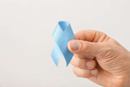 Male hand with blue ribbon on light background. Prostate cancer awareness conceptの写真素材