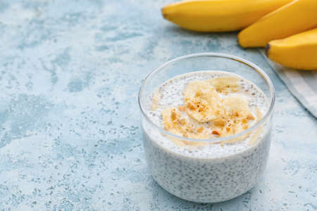 Glass of tasty banana smoothie with chia seeds on color backgroundの写真素材