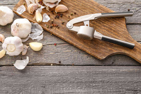 Garlic press with cloves and spices on tableの写真素材