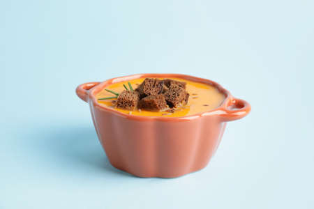 Tasty pumpkin cream soup in pot on color background