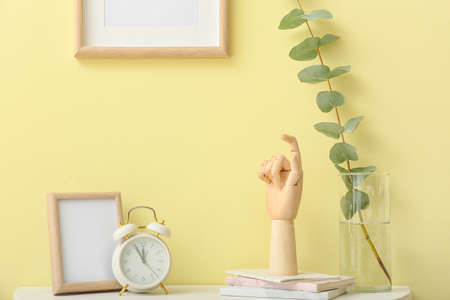 Wooden hand with alarm clock on table in interior of room