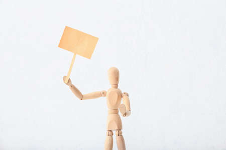 Wooden mannequin with blank placard on light backgroundの写真素材