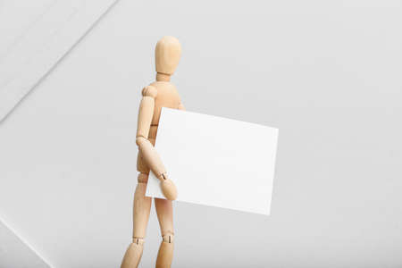 Wooden mannequin with blank poster on light backgroundの写真素材