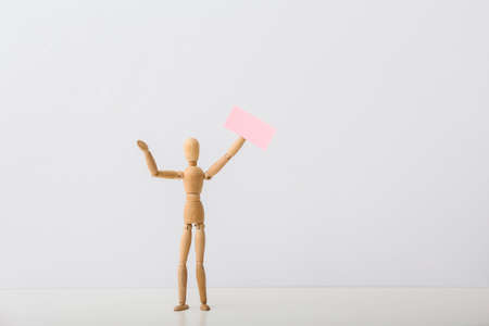 Wooden mannequin with blank placard on light backgroundの写真素材