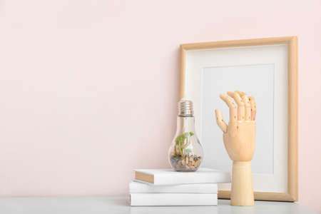 Wooden hand with decorative incandescent lamp on color backgroundの写真素材