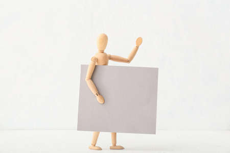 Wooden mannequin with blank poster on light backgroundの写真素材