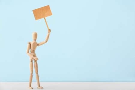 Wooden mannequin with blank placard on color backgroundの写真素材