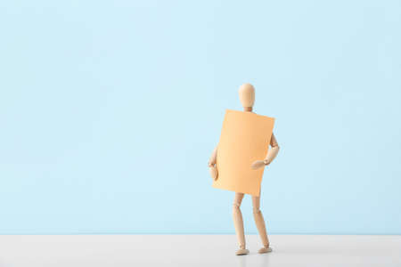 Wooden mannequin with blank poster on color backgroundの写真素材