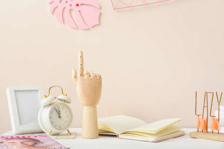 Wooden hand with alarm clock and notebook on table in interior of roomの写真素材